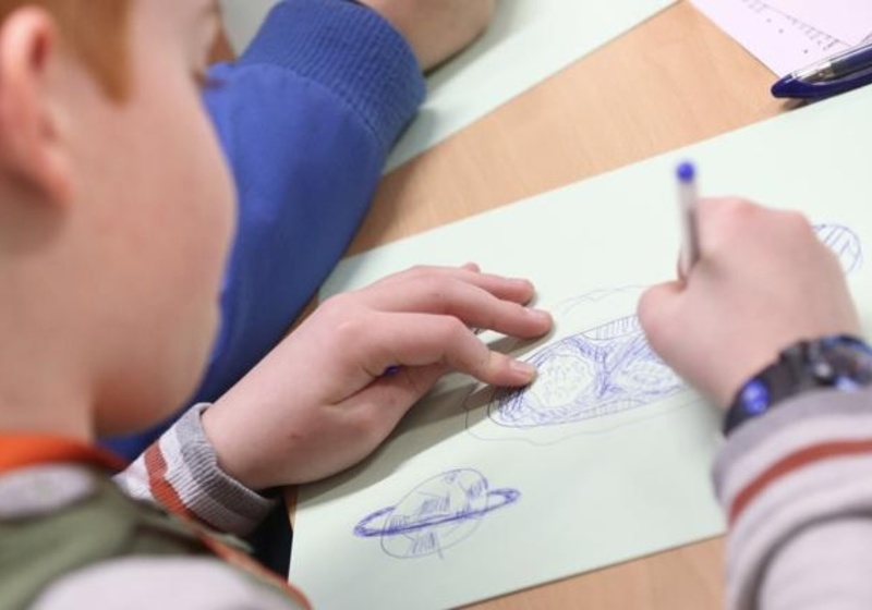A schoolboy drawing a planet