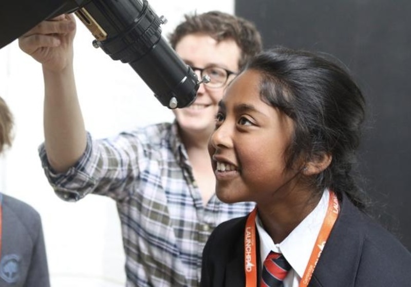 A girl looking through a telescope